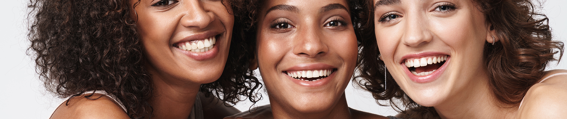 The image is a photograph of a woman with light skin, smiling at the camera. She appears to be in her late twenties or early thirties and has long hair. Her eyes are looking directly at the camera, and she is holding up her index finger near her mouth as if she s making a point or emphasizing something. The background is plain and light-colored, which suggests that this could be a stock photo used for various purposes such as advertising, personal branding, or lifestyle content.